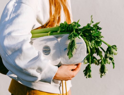 Woman carrying toilet paper under her arm with groceries.