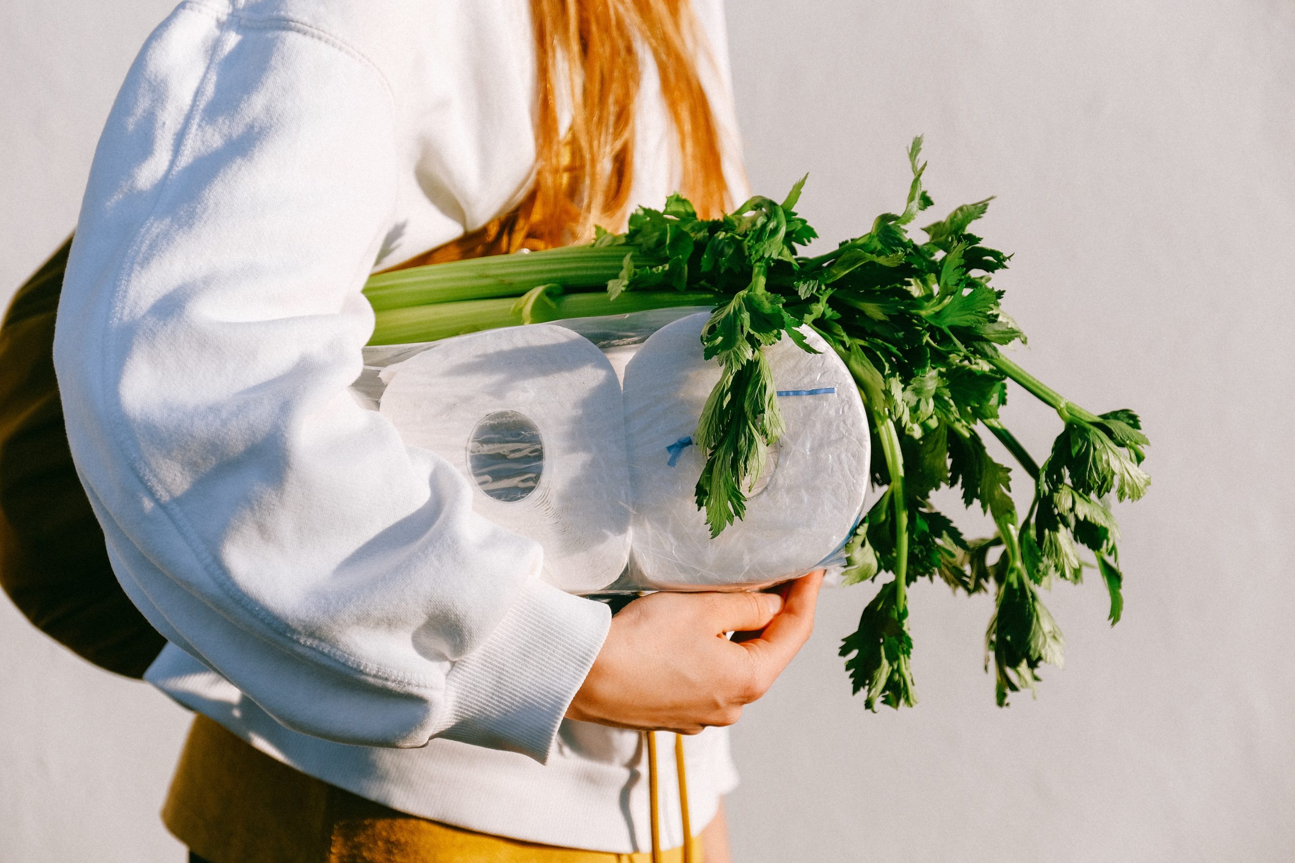 Woman carrying toilet paper under her arm with groceries.